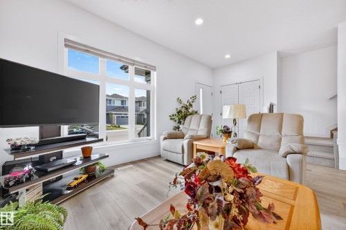 Living area featuring a large multi-pane window, wood-finish flooring, recessed lighting, and white walls - 104 Kidd Crescent, Leduc, AB 