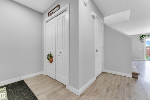 Entryway featuring wood-finish flooring, light gray walls, white trim, and a bi-fold closet - 1750 27 Street, Edmonton, AB 