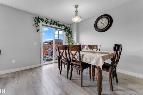 Bright dining area featuring light-toned wood-finish flooring, a contemporary pendant light fixture, and a sliding glass patio door - 1750 27 Street, Edmonton, AB 