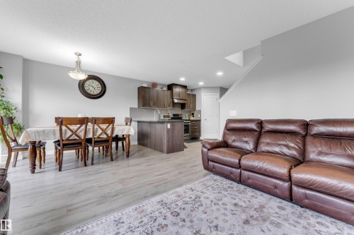 Open-concept living space featuring wood-finish flooring, recessed lighting, and a neutral color palette - 1750 27 Street, Edmonton, AB 