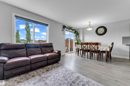 Open-concept living area featuring light-toned flooring and a large window - 1750 27 Street, Edmonton, AB 