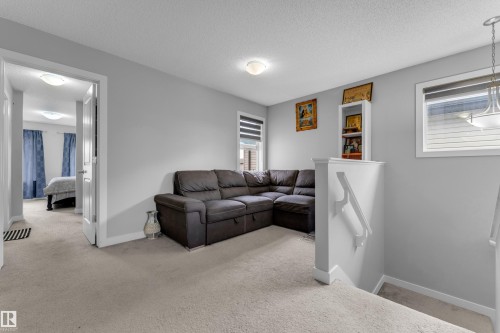 Carpeted upper level lounge area featuring a corner sectional and window treatments - 1750 27 Street, Edmonton, AB 