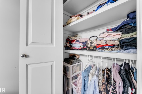 White interior door with a brushed nickel knob opening to a closet featuring white shelving and a hanging rod - 1750 27 Street, Edmonton, AB 