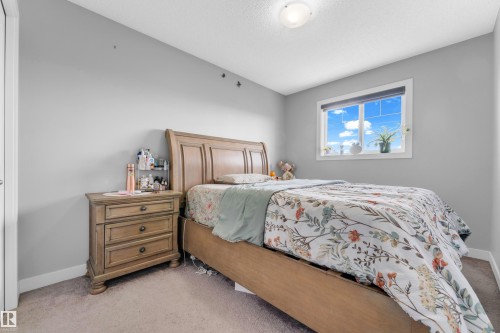 Bedroom featuring a neutral color palette, ceiling-mounted light fixture, white trim, and a window with a roller shade - 1750 27 Street, Edmonton, AB 