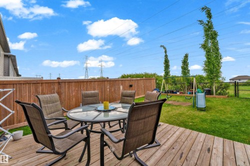 Expansive backyard featuring a wood-finish deck, manicured lawn, and natural wood privacy fencing - 1750 27 Street, Edmonton, AB 