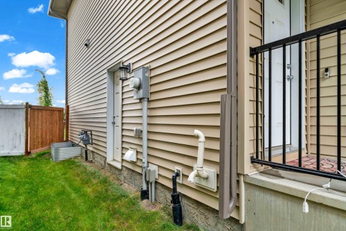 Side exterior featuring tan horizontal siding and a white entry door - 1750 27 Street, Edmonton, AB 