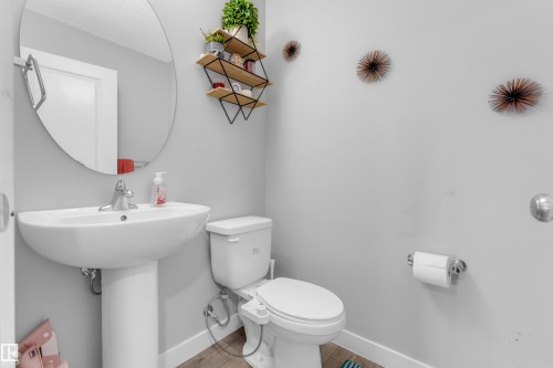 Pedestal sink with chrome faucet, oval mirror, and wood-finish flooring - 1750 27 Street, Edmonton, AB 
