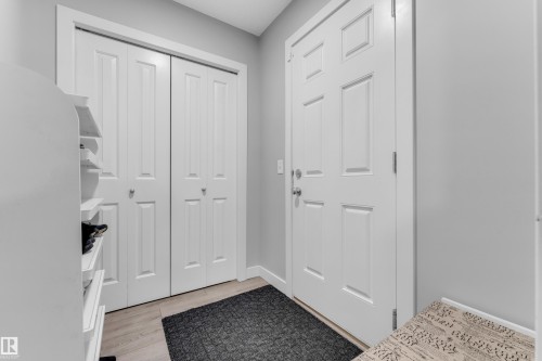 Bright entryway featuring a paneled door, bi-fold closet doors, light wood-finish flooring, and light gray walls - 1750 27 Street, Edmonton, AB 