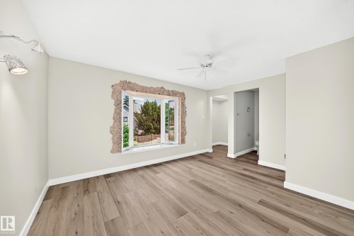 Spacious room featuring wood-finish flooring, light-toned walls, and a bay window - 18636 71 Avenue, Edmonton, AB 