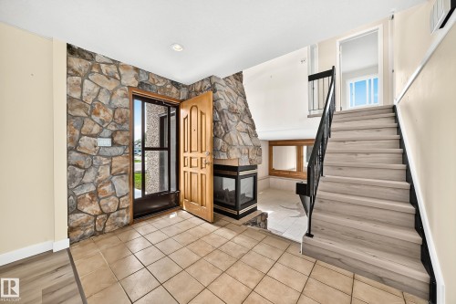 Entryway featuring stone accent wall, tile flooring, and a built-in fireplace - 18636 71 Avenue, Edmonton, AB 