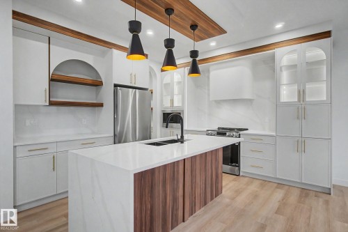 Modern kitchen featuring a large central island with a wood-finish base and a white countertop - 4 Willow Heights Drive, Stony Plain, AB 