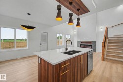 Modern kitchen island featuring a waterfall-edge countertop, integrated double sink with a gooseneck faucet, and rich wood-finish cabinetry with gold-tone hardware - 