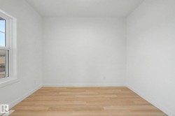 Bright interior space featuring a window with white trim, wood-finish flooring, white baseboards, and neutral wall finishes - 