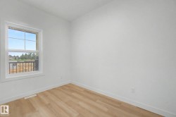 Room featuring wood-finish flooring, white walls, and a white-framed window with grilles - 