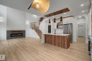 Open-concept living space featuring wood-finish flooring, a contemporary fireplace with slate-look surround, and a kitchen island with stone countertop - 4 Willow Heights Drive, Stony Plain, AB 