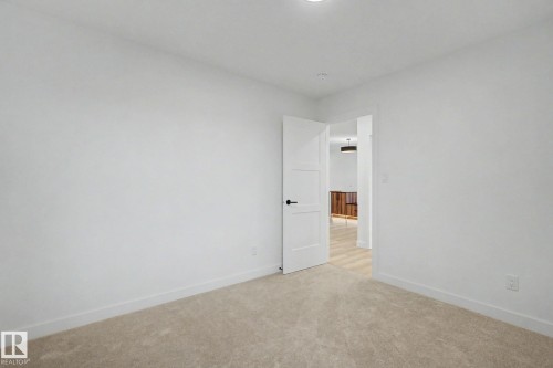 Room featuring neutral-toned carpeting, white walls, and a modern three-panel interior door with matte black hardware - 4 Willow Heights Drive, Stony Plain, AB 