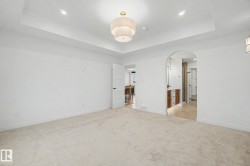 Spacious room featuring light-colored carpeting and a tray ceiling with recessed lighting - 