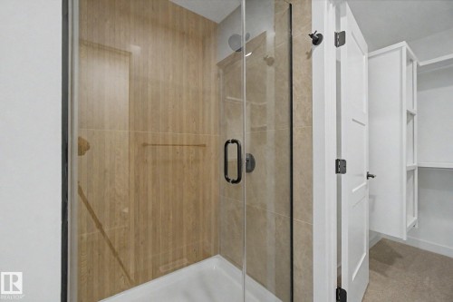 Glass-enclosed shower with wood-finish tile surround and a matte black shower head - 4 Willow Heights Drive, Stony Plain, AB 