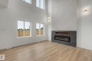 Spacious interior featuring soaring ceilings, a striking electric fireplace with a dark tile surround, a built-in wood-finish media niche, and tall windows providing abundant natural light - 4 Willow Heights Drive, Stony Plain, AB 