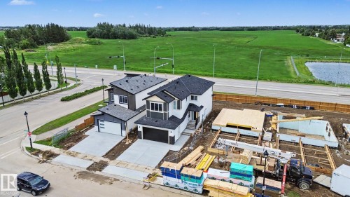 Modern two-story residence featuring a dark gray and white exterior, a two-car attached garage, and paved driveway - 4 Willow Heights Drive, Stony Plain, AB 