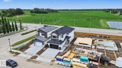 Modern two-story residence featuring a dark gray and white exterior, a two-car attached garage, and paved driveway - 
