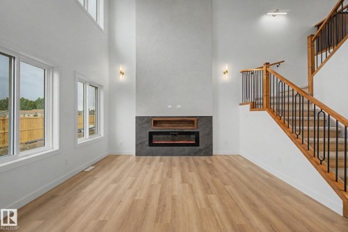 Spacious living area featuring a two-story ceiling, wood-finish flooring, and multiple windows - 4 Willow Heights Drive, Stony Plain, AB 