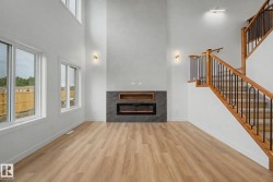 Spacious living area featuring a two-story ceiling, wood-finish flooring, and multiple windows - 