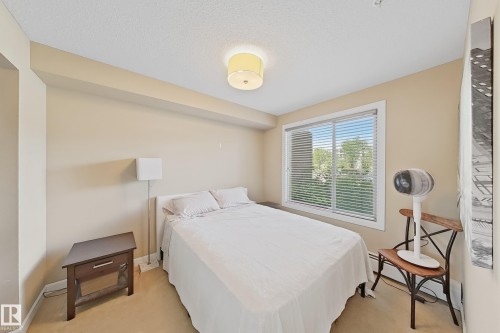 Bedroom featuring a large window with white blinds, neutral-toned walls, and carpet flooring - 117 3715 Whitelaw Lane, Edmonton, AB 