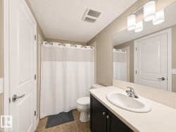Bathroom vanity featuring a single basin sink, chrome faucet, and dark wood cabinetry - 