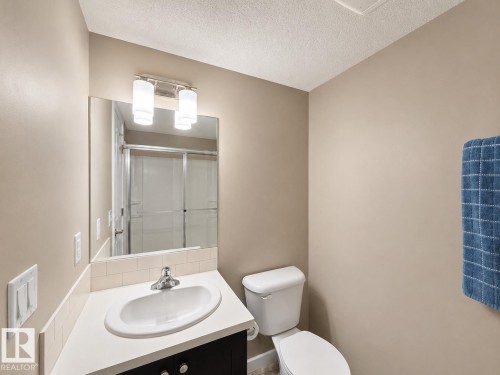 Bathroom featuring a modern vanity with a white countertop, undermount sink, and chrome faucet - 117 3715 Whitelaw Lane, Edmonton, AB 