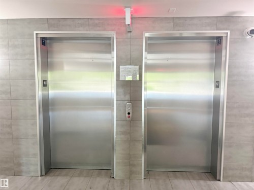 Dual stainless steel elevators featuring sleek metal finishes and a light tile surround - 117 3715 Whitelaw Lane, Edmonton, AB 