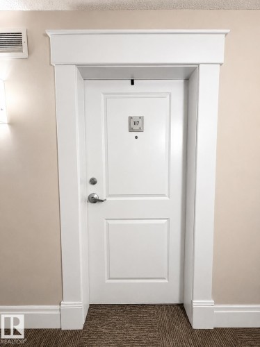 White paneled door with brushed nickel hardware, framed by substantial white door casing and crown molding - 117 3715 Whitelaw Lane, Edmonton, AB 