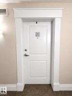 White paneled door with brushed nickel hardware, framed by substantial white door casing and crown molding - 