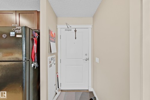 Entryway featuring a white paneled door with brushed nickel hardware, neutral wall paint, and wood-finish flooring - 117 3715 Whitelaw Lane, Edmonton, AB 