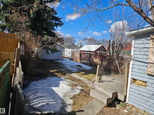 Expansive backyard featuring a detached garage, wooden privacy fencing, and a multi-level wooden deck - 11406 88 Street, Edmonton, AB 