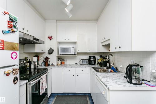 U-shaped kitchen with white cabinetry, white subway tile backsplash, and stone-finish countertops - 11105 81 Avenue, Edmonton, AB 