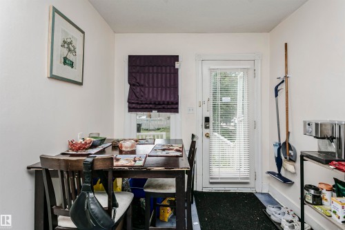 Dining space featuring a white exterior door with integrated blinds, a window with a roman shade, and light-toned wall finishes - 11105 81 Avenue, Edmonton, AB 