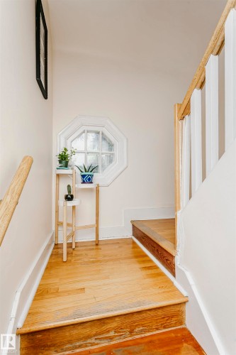 Hardwood flooring with a white octagonal window and natural wood handrail - 11105 81 Avenue, Edmonton, AB 
