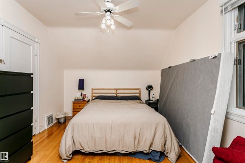 Bedroom featuring wood-finish flooring, a ceiling fan with light fixture, and an angled ceiling - 11105 81 Avenue, Edmonton, AB 