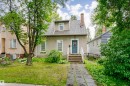 Traditional two-story residence with a stucco exterior, featuring a prominent blue entry door, white-trimmed windows, and a shingle roof with a dormer - 11105 81 Avenue, Edmonton, AB 