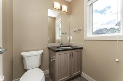 Bathroom featuring a wood-finish vanity with a dark countertop and integrated sink - 