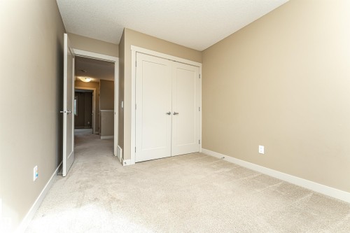 Neutral tone walls with white trim, light-colored carpet flooring, and a double-door closet with brushed nickel hardware - 2397 Glenridding Boulevard, Edmonton, AB 