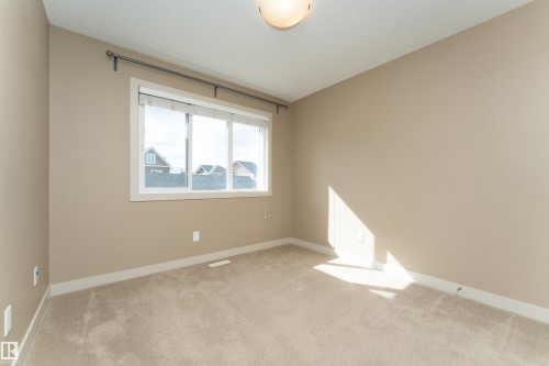 Room featuring light beige carpeting, neutral wall color, and a three-pane window with white trim - 2397 Glenridding Boulevard, Edmonton, AB 
