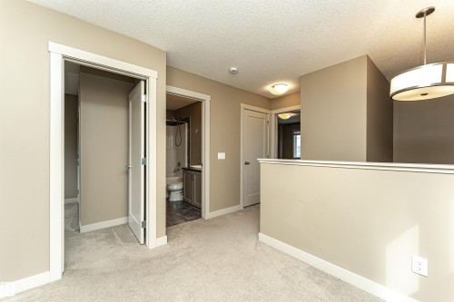 Carpeted hallway featuring warm neutral wall tones and white trim - 2397 Glenridding Boulevard, Edmonton, AB 