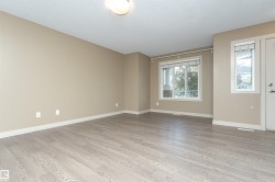 Spacious room featuring wood-finish flooring, neutral-toned walls, and white baseboards - 