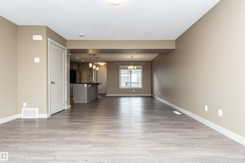 Open-concept living space featuring wood-finish flooring, neutral wall tones, and white trim - 2397 Glenridding Boulevard, Edmonton, AB 