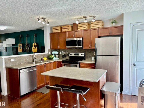 Kitchen featuring wood-finish cabinetry, stainless steel appliances, and a central island with a breakfast bar - 184 1804 70 Street, Edmonton, AB 