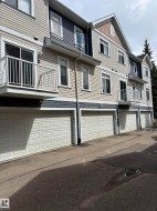 Multi-level exterior featuring light beige and dark blue horizontal siding, white trim, multiple balconies with white railings, and individual garage doors - 