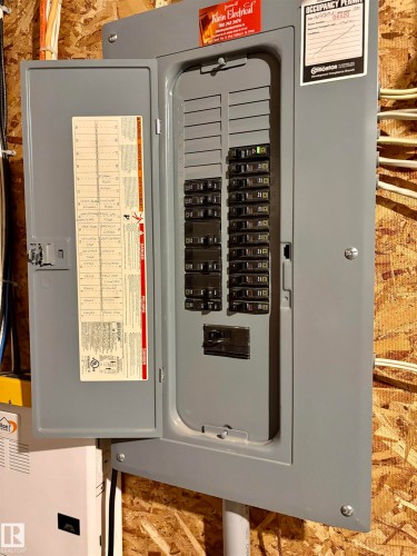 Electrical panel featuring a gray metal enclosure, multiple circuit breakers, an interior door with a circuit directory, and visible wiring - 184 1804 70 Street, Edmonton, AB 