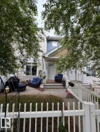 Cream siding exterior with a light blue upper accent, gabled entryways, and a white picket fence - 